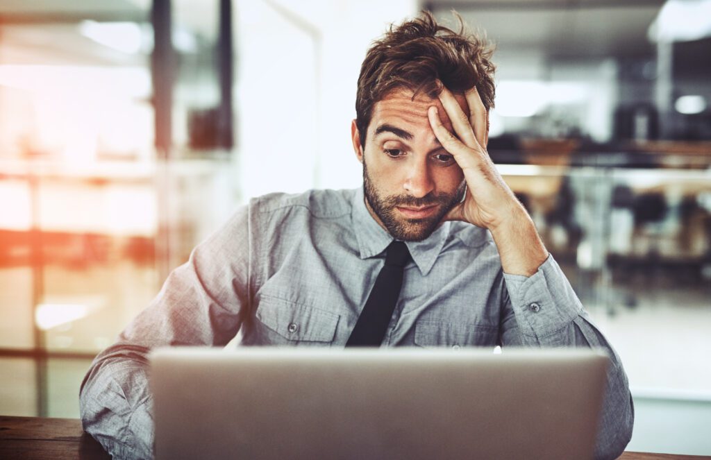 Businessman, laptop and headache in stress, burnout or overworked from strain at the office desk. Frustrated man person or employee with bad head pain or confused working on computer at the workplace Businessman, laptop and headache in stress, burnout or overworked from strain at the office desk. Frustrated man person or employee with bad head pain or confused working on computer at the workplace.